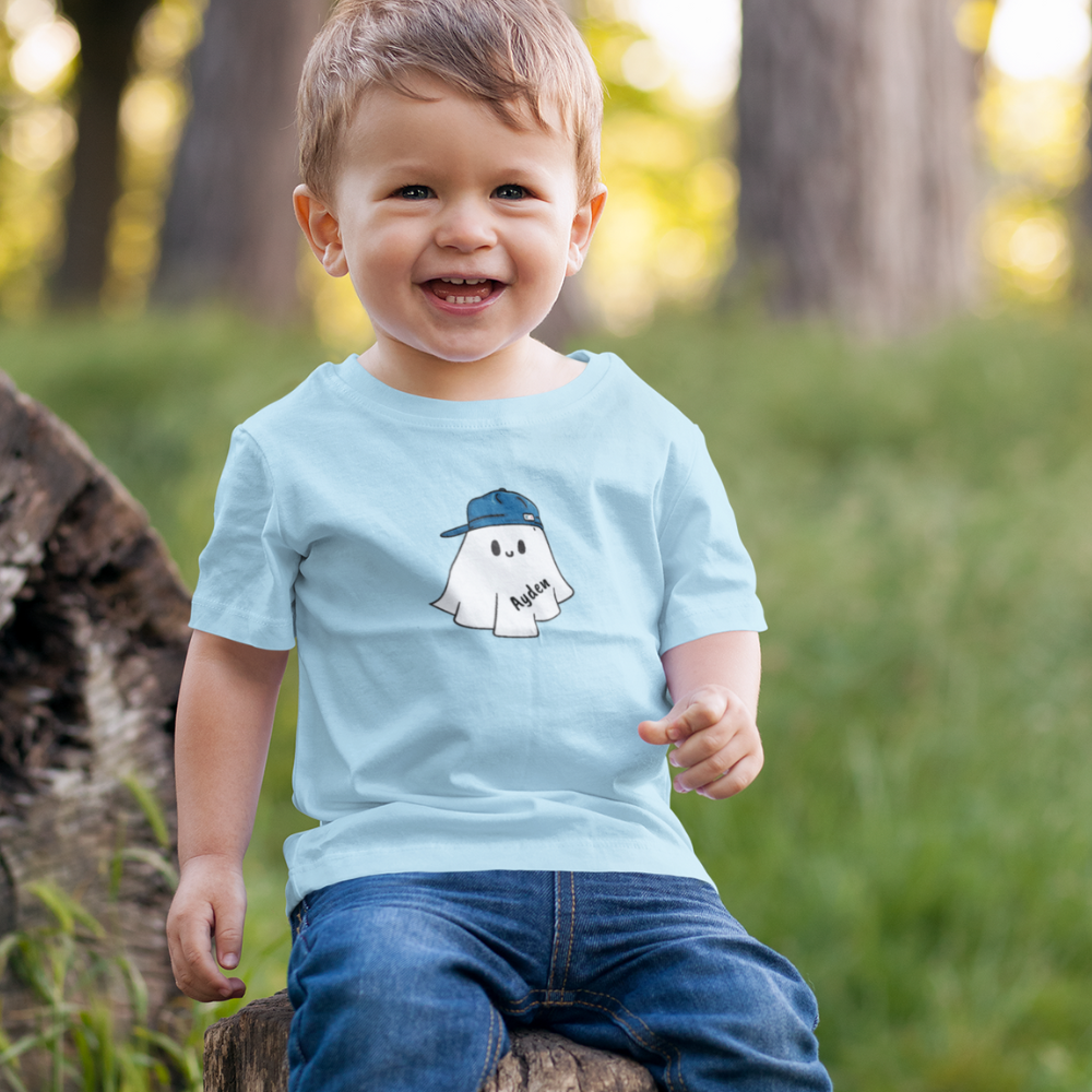Child wearing a light blue t-shirt with a ghost graphic outdoors
