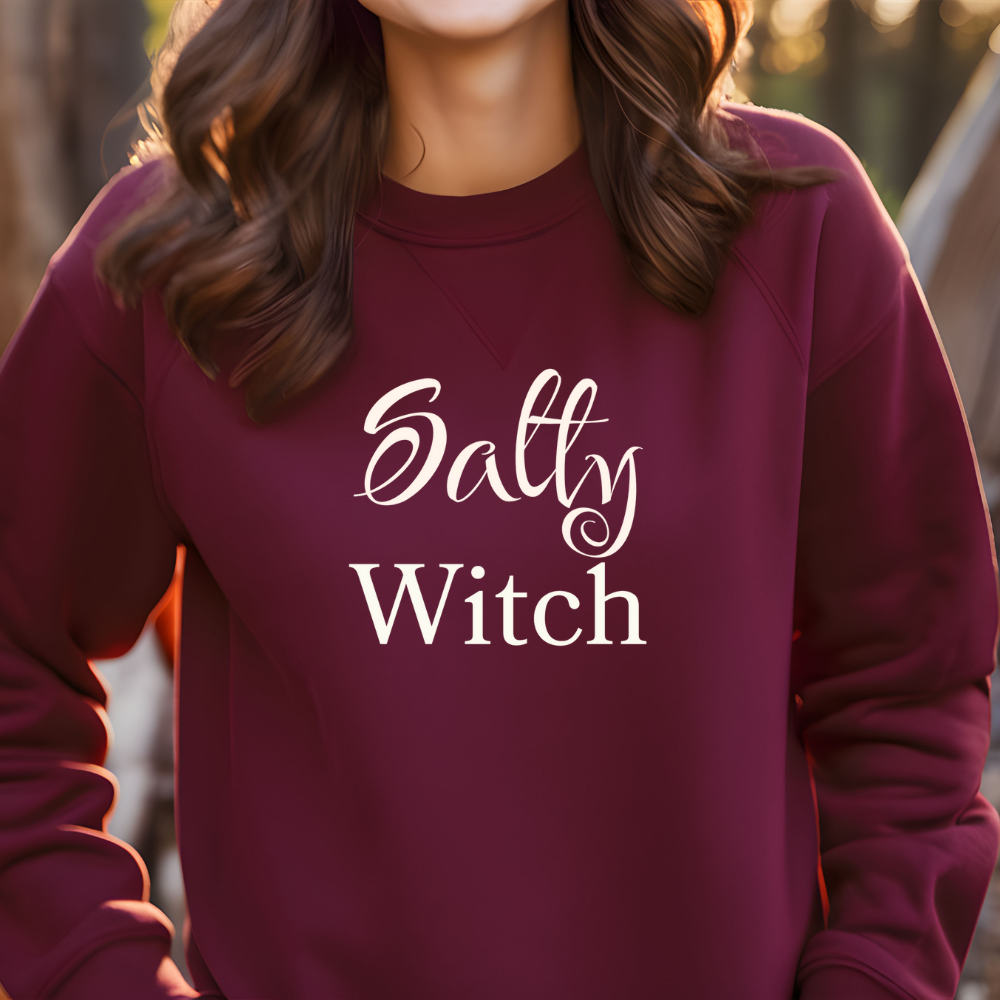 Maroon sweatshirt with 'Salty Witch' text worn by a person outdoors.