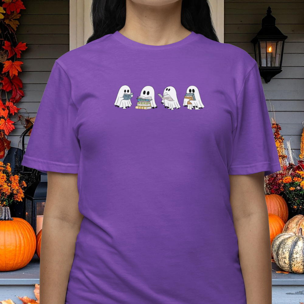 Person wearing a purple t-shirt with cartoon ghosts in front of Halloween decorations.