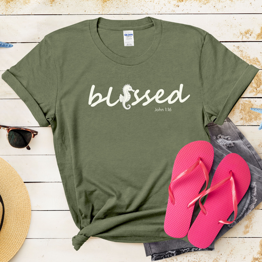 Green t-shirt with 'blessed' text, pink flip-flops, and sunglasses on a wooden surface