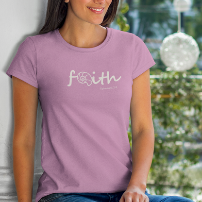 Woman wearing a purple t-shirt with 'faith' printed on it, sitting outdoors.