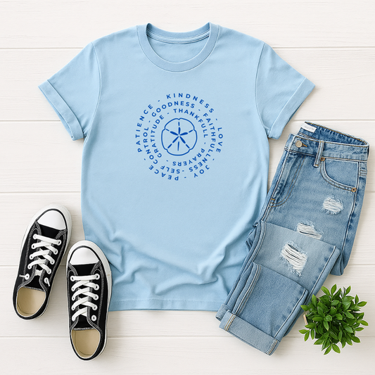 Light blue t-shirt with a graphic design, paired with jeans and black sneakers on a white wooden surface.