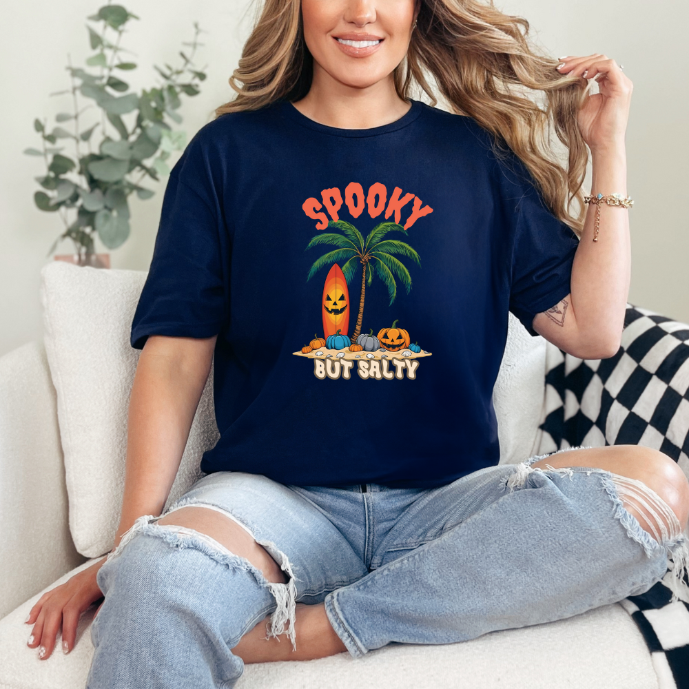 Person wearing a navy blue t-shirt with a Halloween-themed design, sitting on a couch.