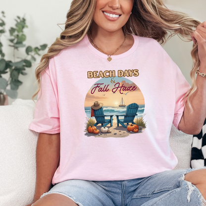 Person wearing a pink t-shirt with 'Beach Days & Fall Have' design, sitting on a couch.