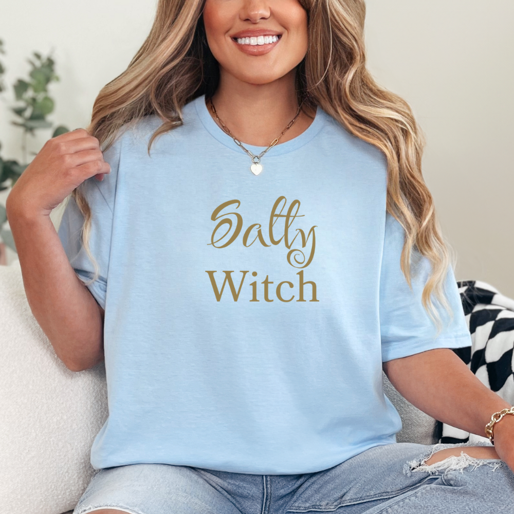Woman wearing a light blue t-shirt with 'Salty Witch' text, sitting on a couch.