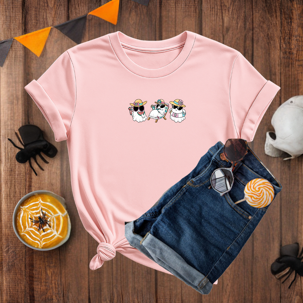Pink t-shirt with cartoon design on a wooden surface with Halloween decorations.