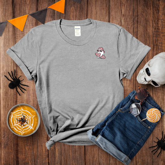 Gray t-shirt with a ghost design on a wooden surface with Halloween decorations.