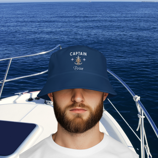 Man wearing a navy blue 'CAPTAIN' hat on a boat with blue ocean in the background