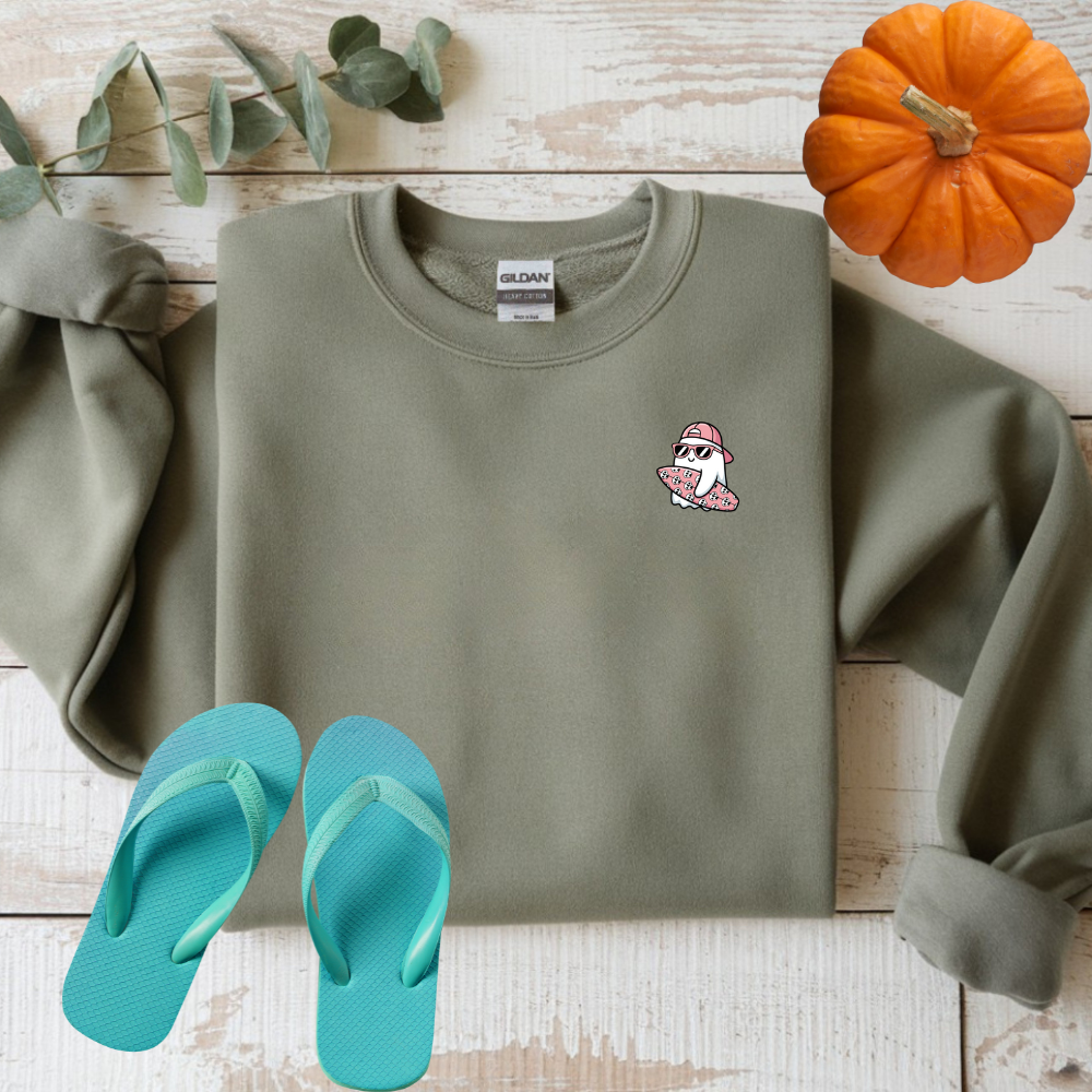 Green sweatshirt with a small logo, green flip-flops, and a small pumpkin on a wooden surface.