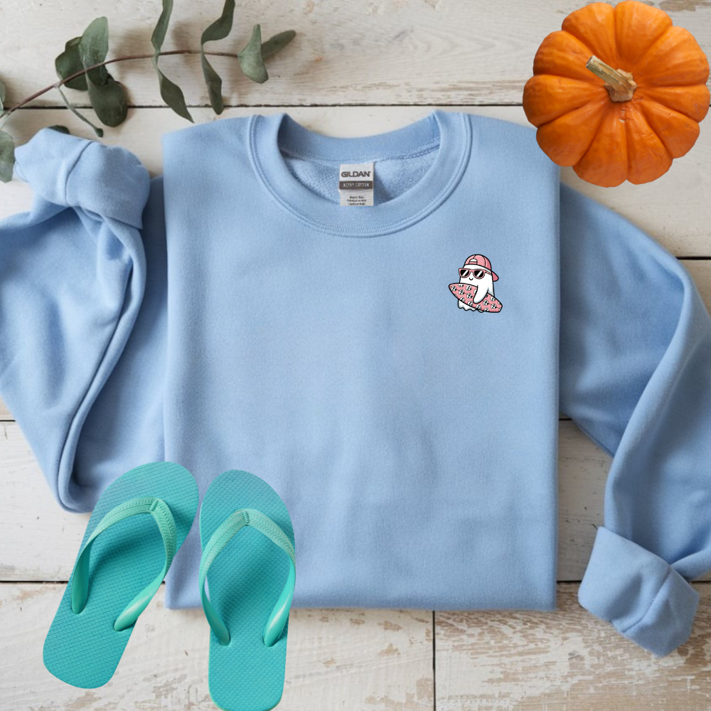 Light blue sweatshirt with a cartoon character, green flip-flops, and a small pumpkin on a wooden surface.