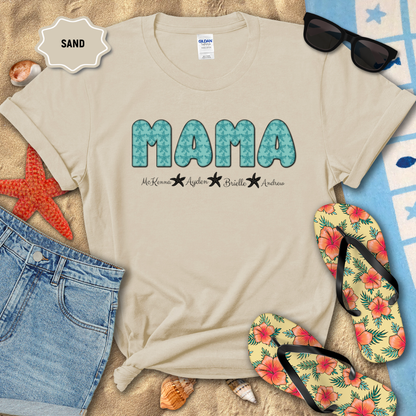 Beige t-shirt with 'MAMA' text on a sandy background with beach accessories.
