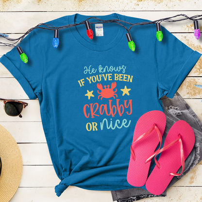 Blue t-shirt with humorous text design, pink flip-flops, and festive lights on a wooden surface.