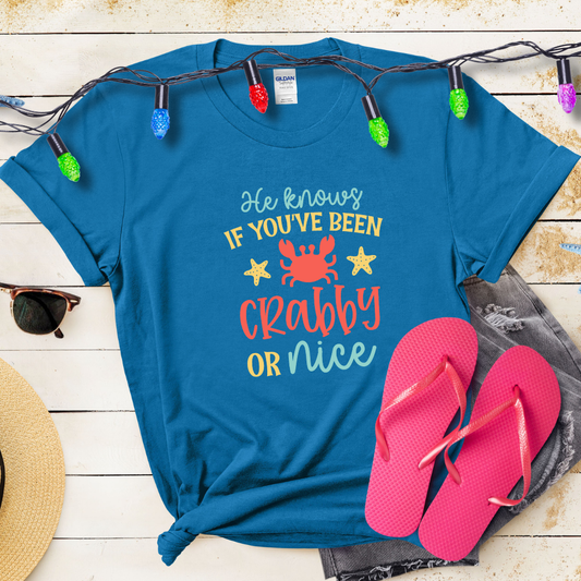 Blue t-shirt with humorous text design, pink flip-flops, and festive lights on a wooden surface.