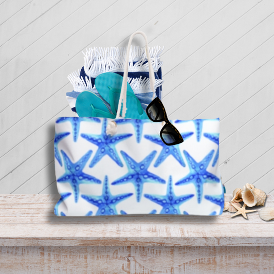 Tote bag with blue starfish pattern on a wooden surface with a light gray background