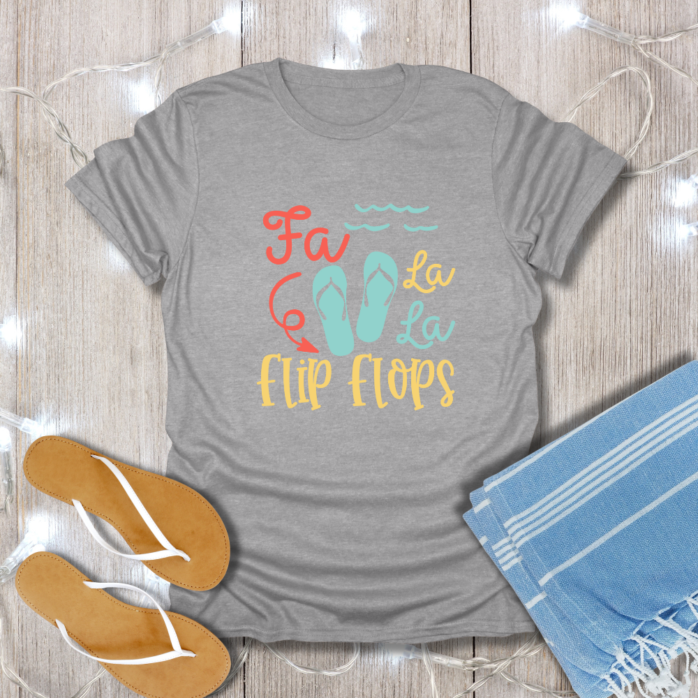 Gray t-shirt with 'Fa La La Flip Flops' text and sandals on a wooden surface