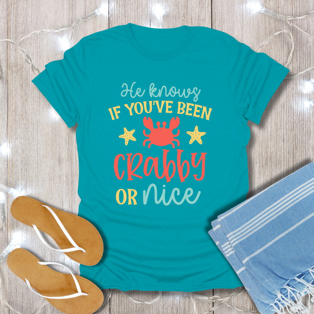 Teal t-shirt with a humorous design on a wooden surface with flip-flops and a towel.