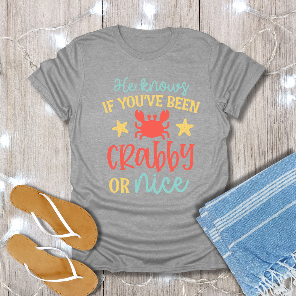 Gray t-shirt with colorful text design on a wooden surface with flip-flops and a towel.