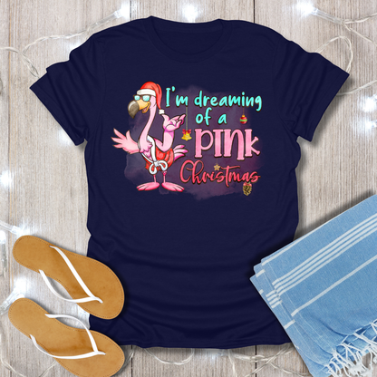 Navy blue t-shirt with flamingo graphic and text on a wooden surface with flip-flops and a towel.