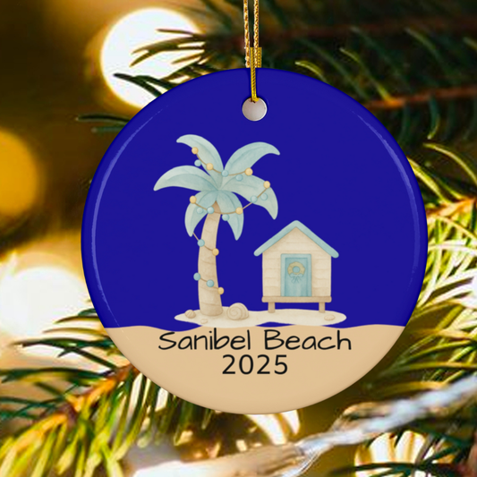 Decorative ornament with palm tree and beach hut design, featuring 'Sanibel Beach 2025' text, hanging on a Christmas tree.