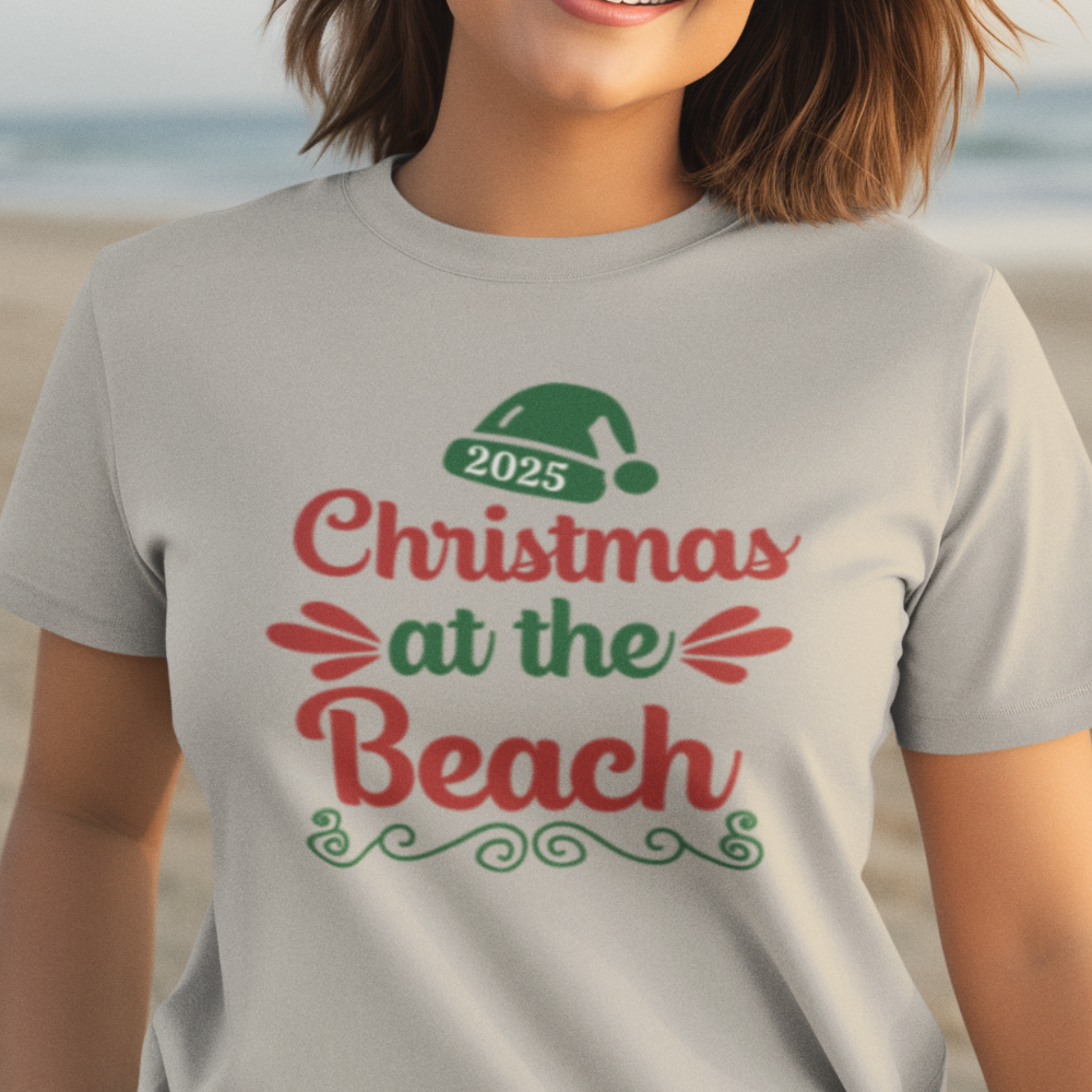 Person wearing a t-shirt with 'Christmas at the Beach 2025' text on a beach background