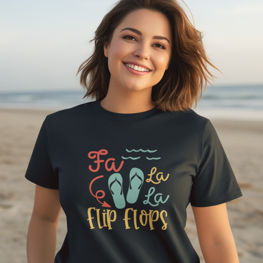 Woman wearing a black t-shirt with 'Fa La La Flip Flops' design on a beach.