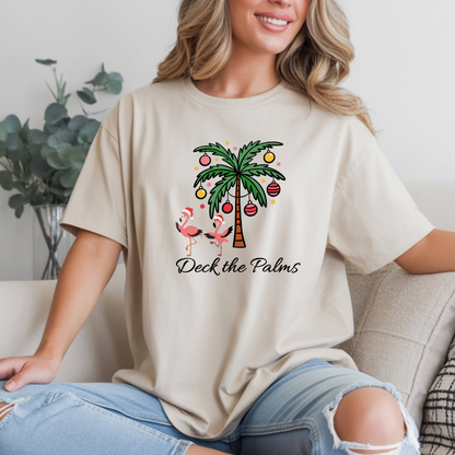 Person wearing a beige t-shirt with a palm tree and flamingo design, sitting on a couch.