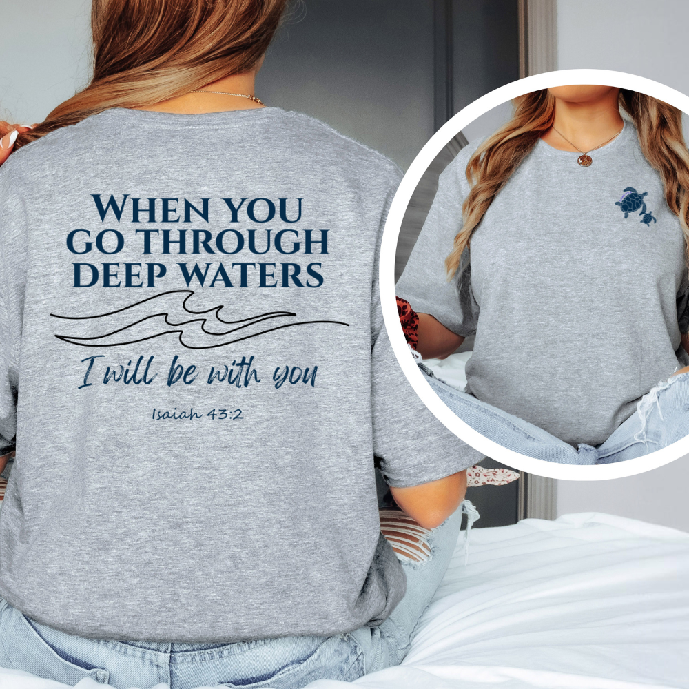 Gray t-shirt with motivational quote on the back, worn by a person sitting on a bed.