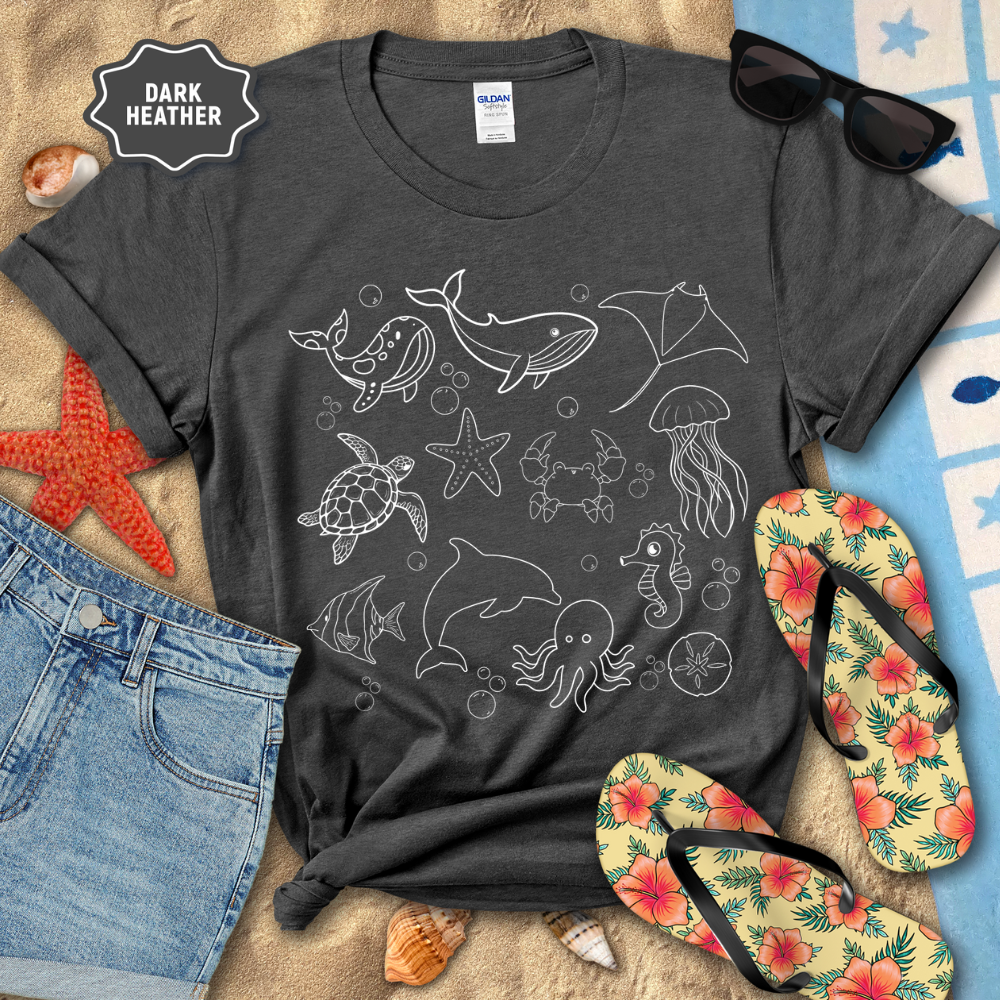 Dark Heather t-shirt with ocean-themed designs on a beach setting with sunglasses, flip-flops, and beach accessories.