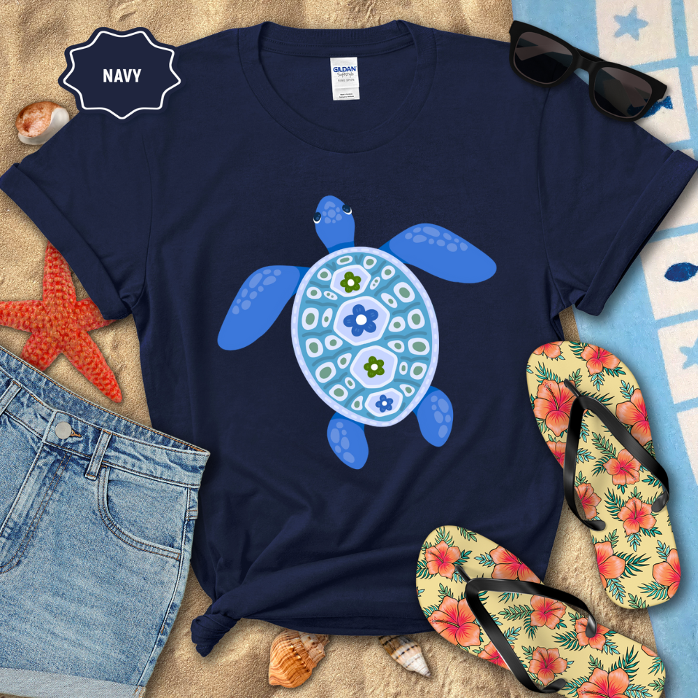 Navy t-shirt with a turtle design on a beach-themed background with sunglasses, flip-flops, and starfish.