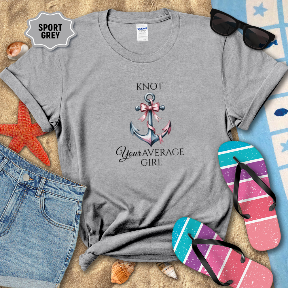 Gray t-shirt with 'Knot Your Average Girl' design on a sandy background with beach accessories.