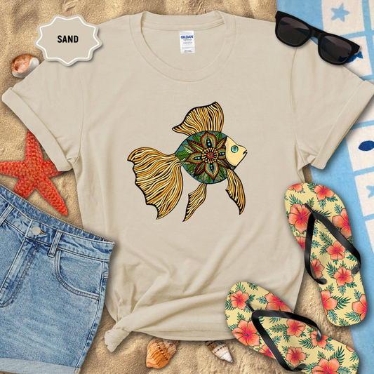 Beige t-shirt with a colorful fish design, sunglasses, and flip-flops on a sandy background.
