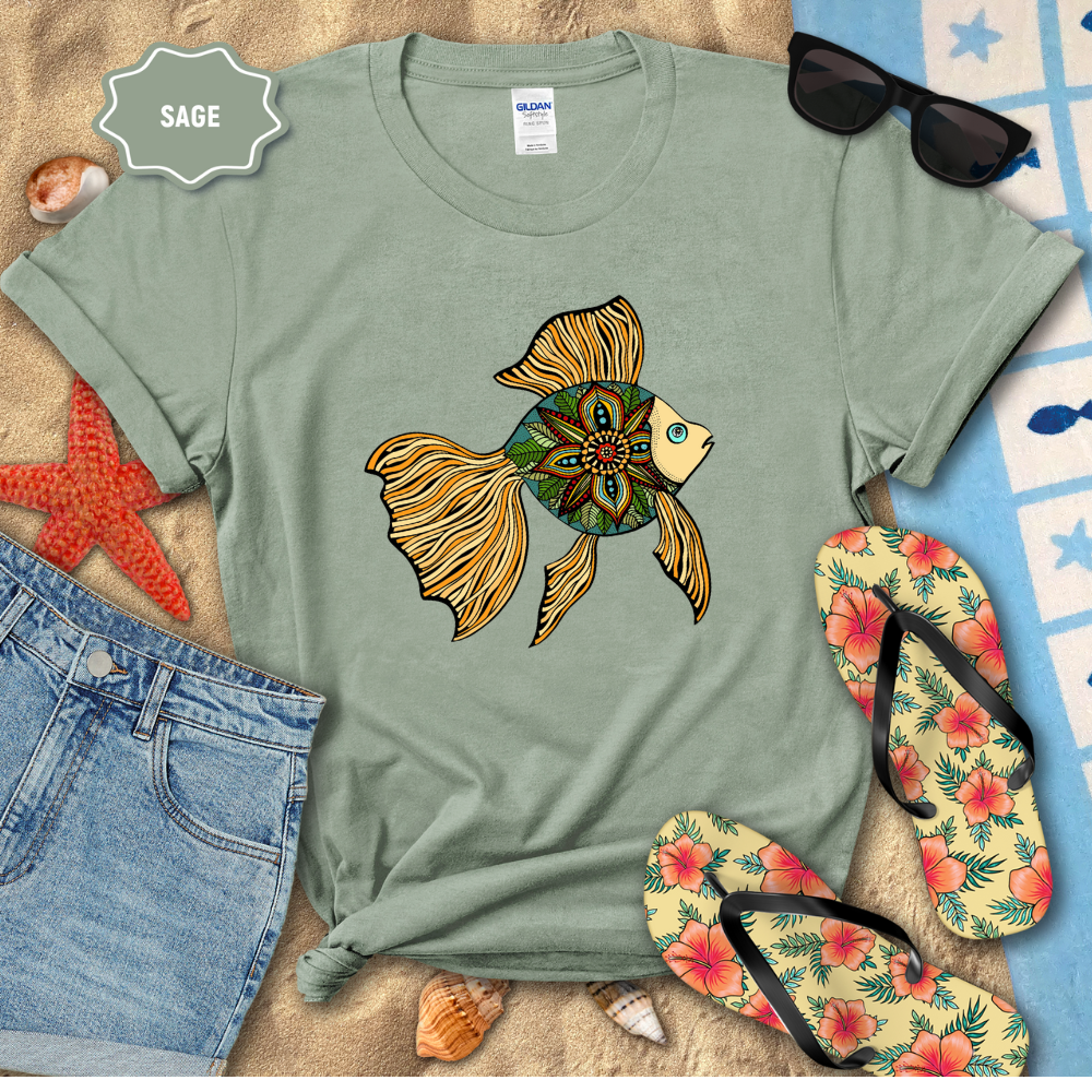 Sage green t-shirt with a colorful fish design, sunglasses, and flip-flops on a sandy surface.