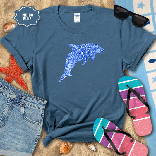 Indigo blue t-shirt with dolphin design on a beach setting with sunglasses, flip-flops, and denim shorts.