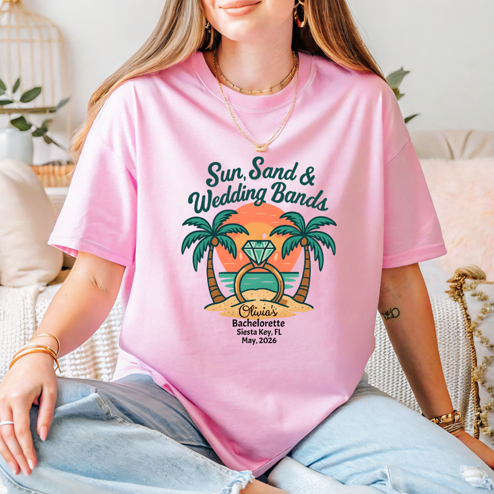 Person wearing a pink t-shirt with a tropical design and text.