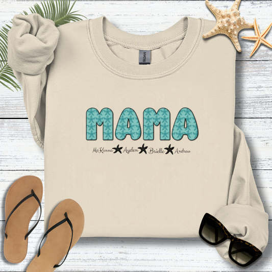 Beige sweatshirt with 'MAMA' print on a wooden surface with flip-flops and starfish.