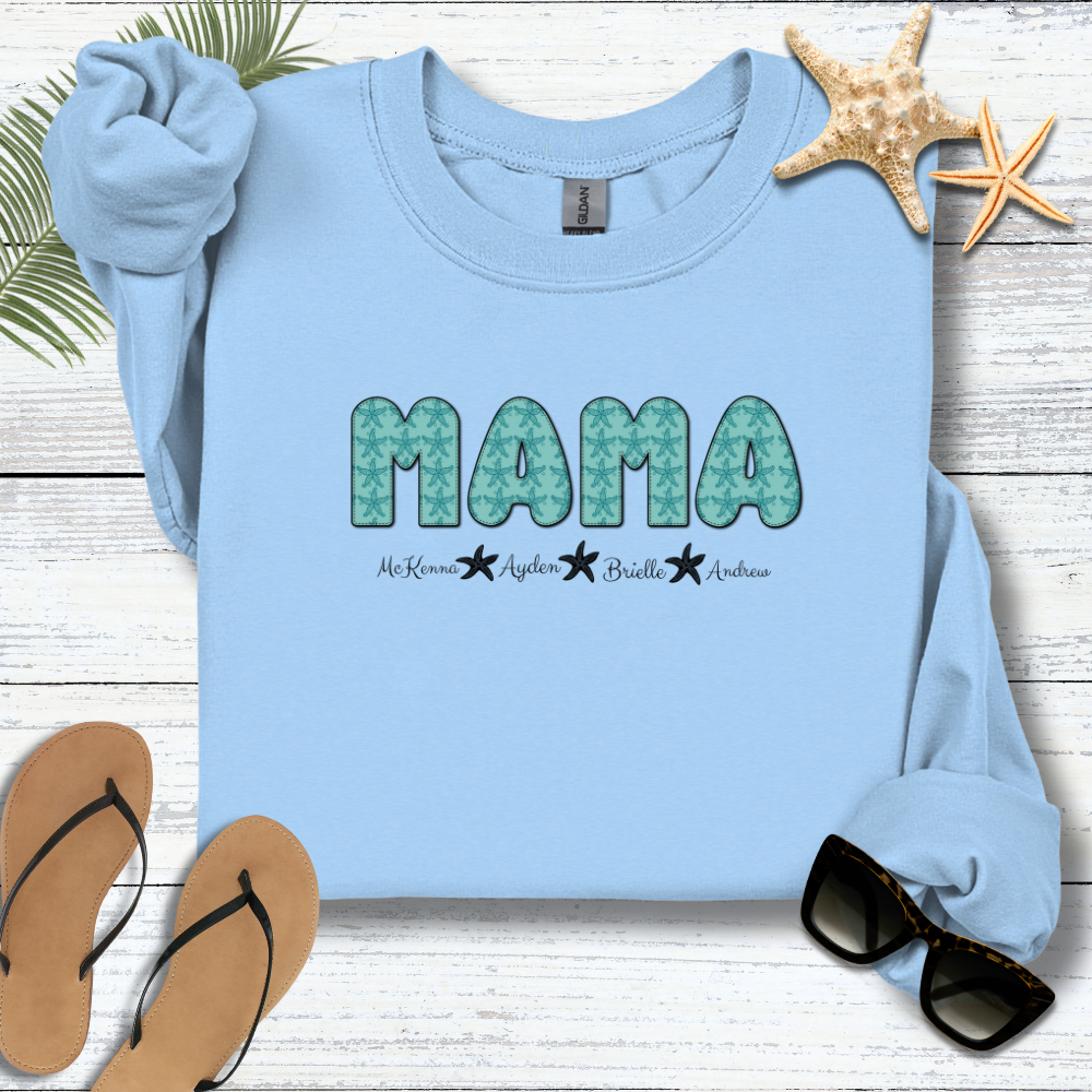 Light blue sweatshirt with 'MAMA' print on a wooden surface with flip-flops and sunglasses.