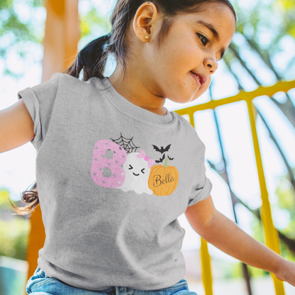 Child wearing a gray t-shirt with Halloween-themed design outdoors
