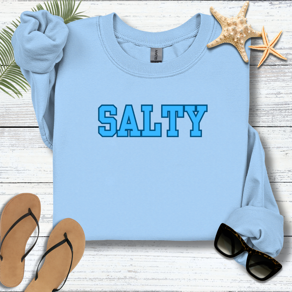 Light blue sweatshirt with 'SALTY' text on a wooden surface with flip-flops and sunglasses.