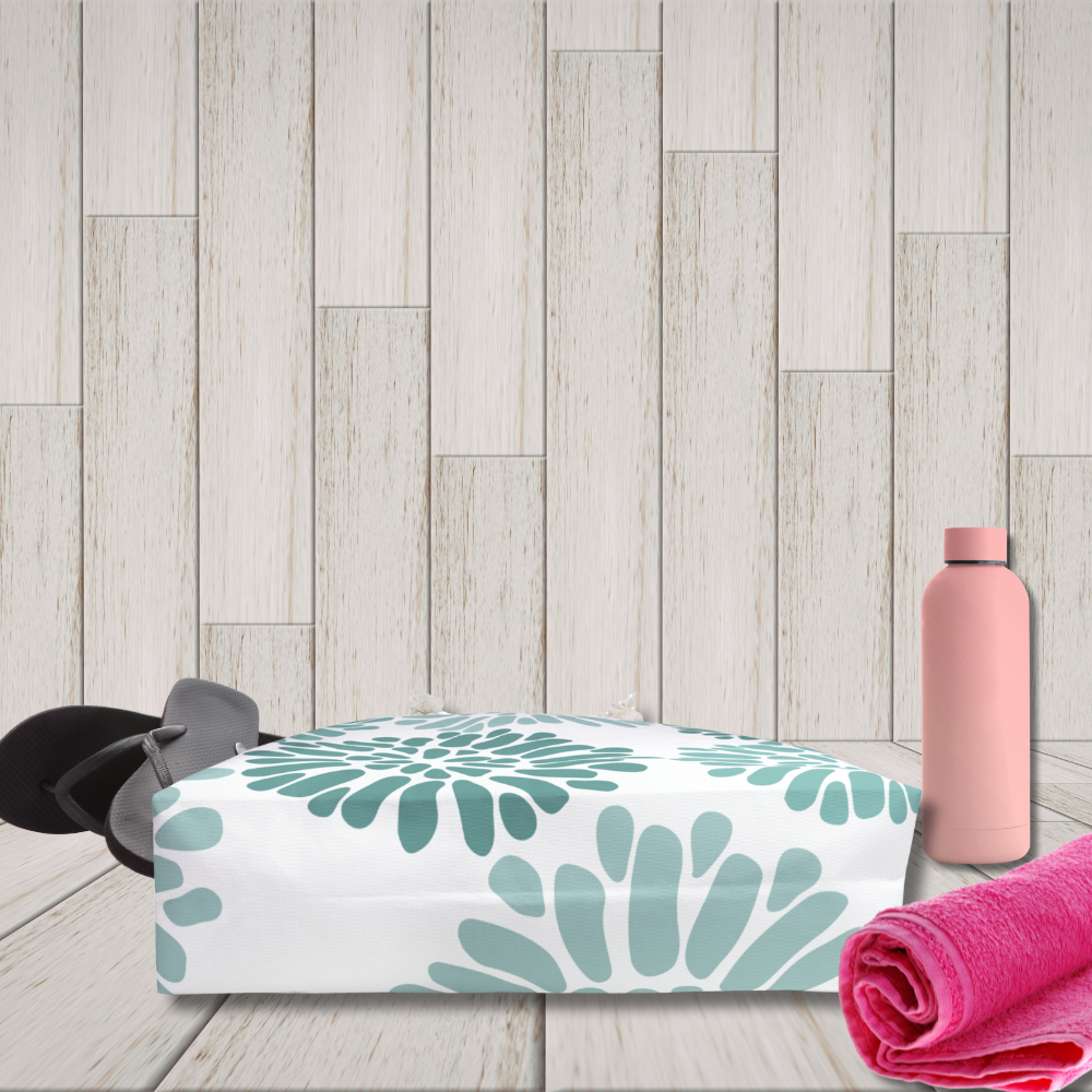 White pouch with green floral pattern, pink water bottle, and pink towel on a wooden floor.