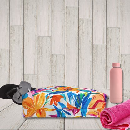 Colorful floral towel, pink water bottle, and black sandals on a wooden floor.