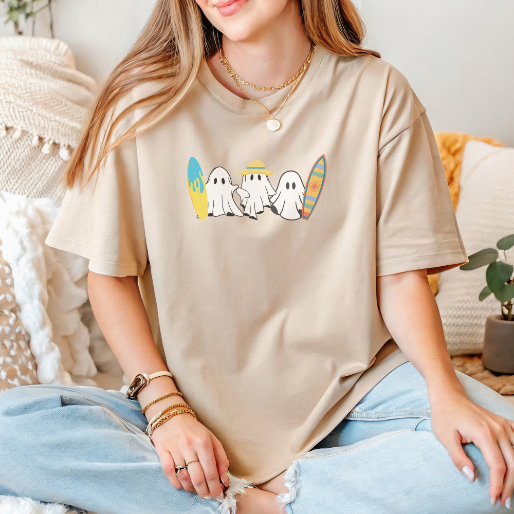 Person wearing a beige t-shirt with cartoon ghosts design, sitting on a couch.