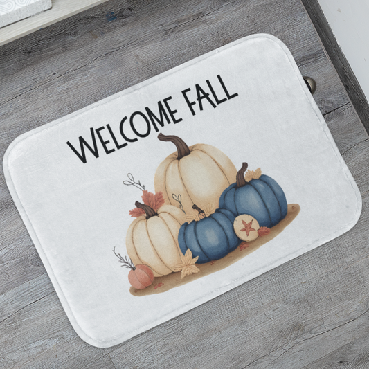 Doormat with 'Welcome Fall' text and pumpkins on a wooden floor.