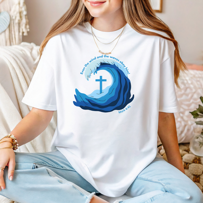 Person wearing a white t-shirt with a blue wave design and cross, sitting on a couch.
