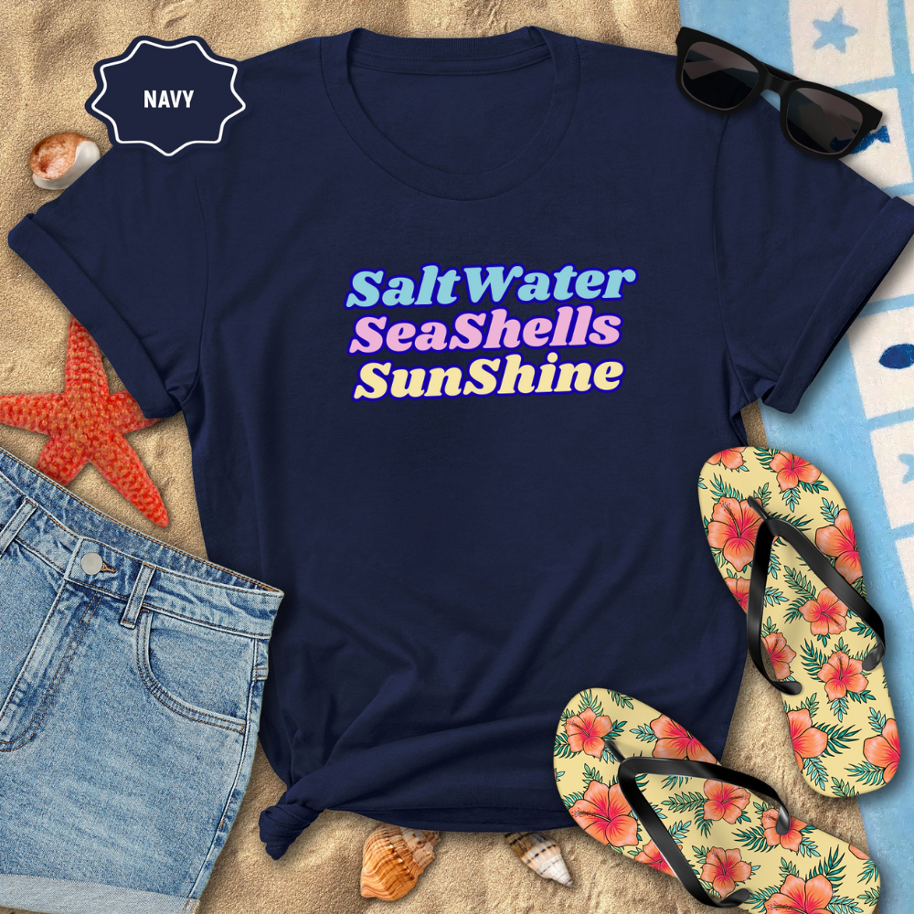 Navy t-shirt with 'Salt Water Seashells Sunshine' text, sunglasses, flip-flops, and beach items on sand.