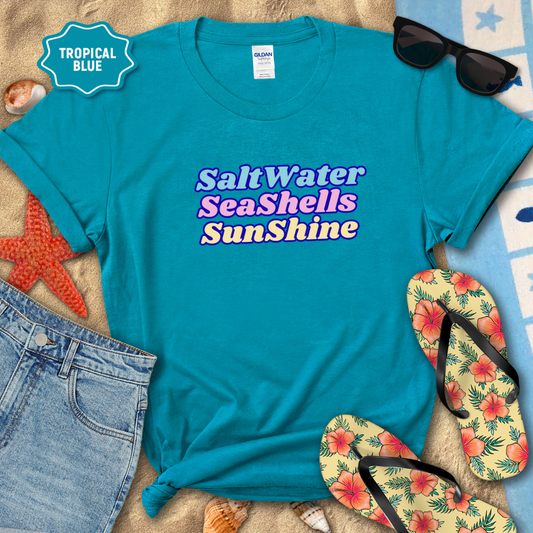 Blue t-shirt with 'Salt Water Sea Shells Sunshine' text, sunglasses, flip-flops, and beach items on a sandy background.