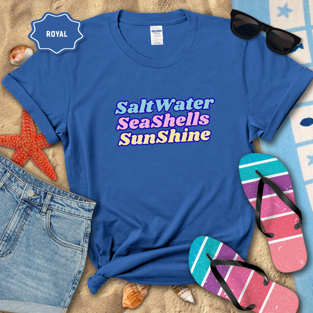 Blue t-shirt with 'Salt Water Sea Shells Sunshine' text, sunglasses, flip-flops, and beach items on sand.
