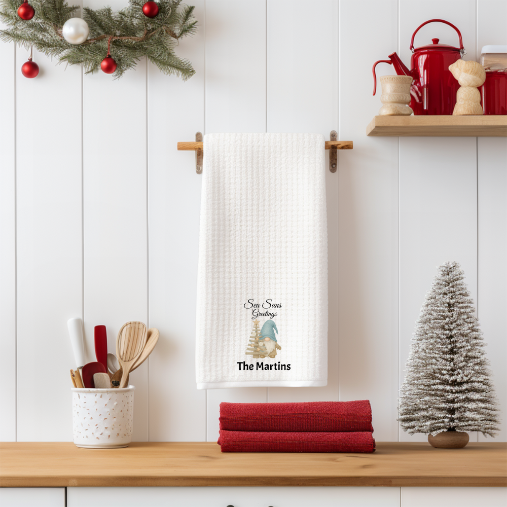 Kitchen setting with a decorative towel, red towels, and Christmas decorations on a white wooden wall.