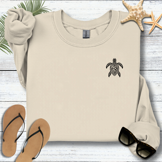 Beige sweatshirt with a turtle design on a wooden surface with flip-flops and starfish.