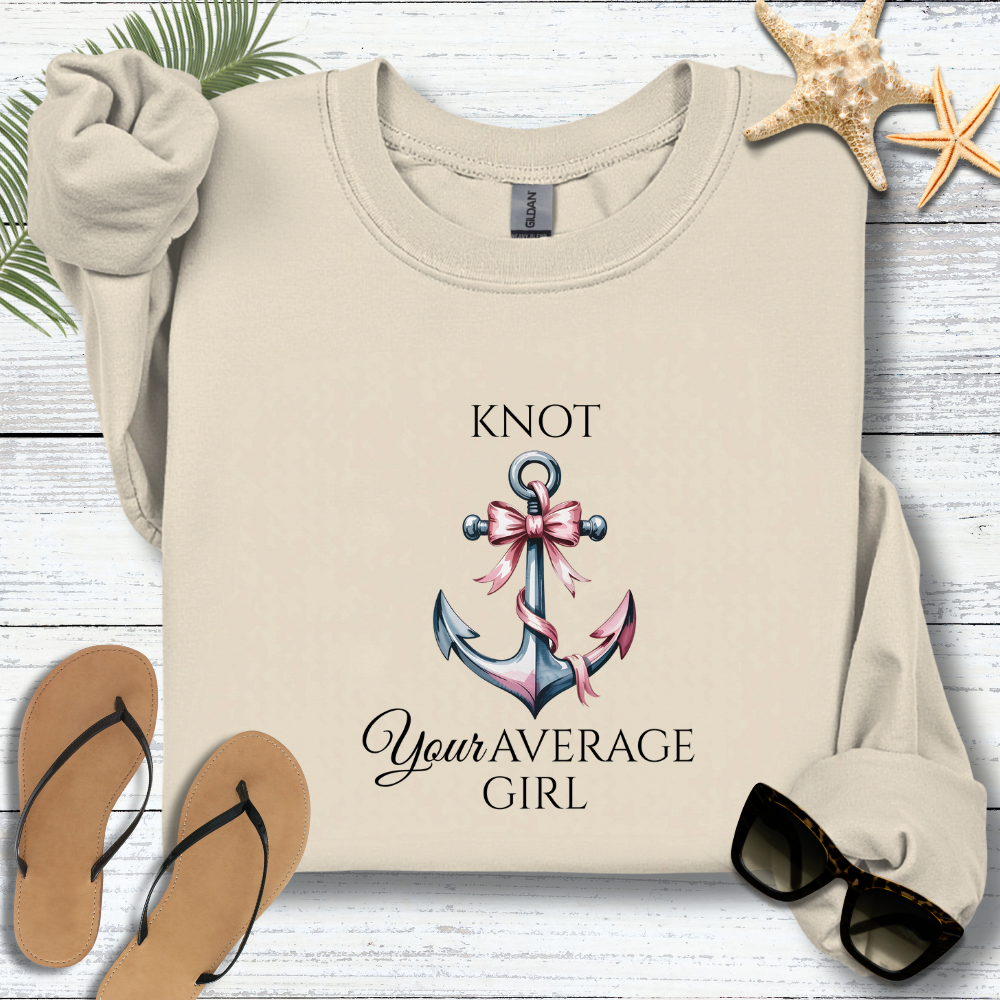 Beige sweatshirt with anchor and bow design and text on a wooden surface with flip-flops and starfish.