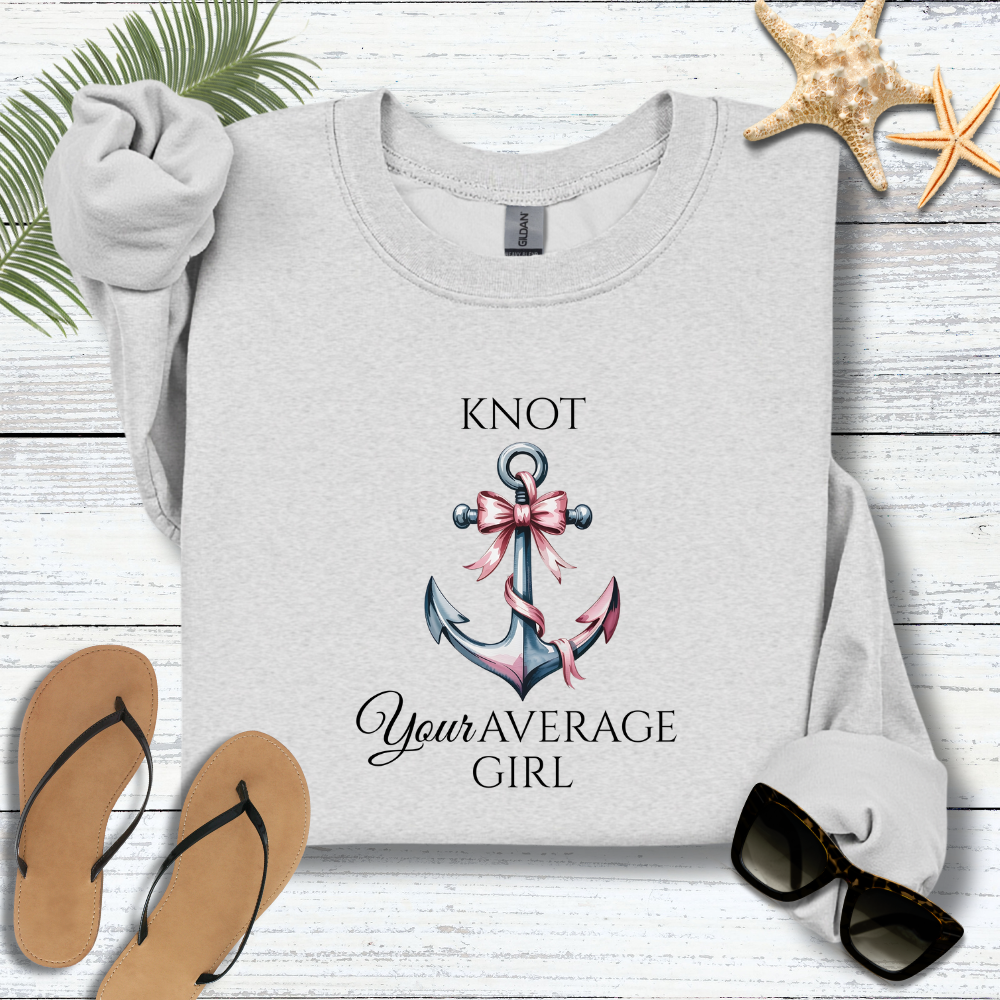 Gray sweatshirt with anchor design and text on a wooden surface with flip-flops and sunglasses.